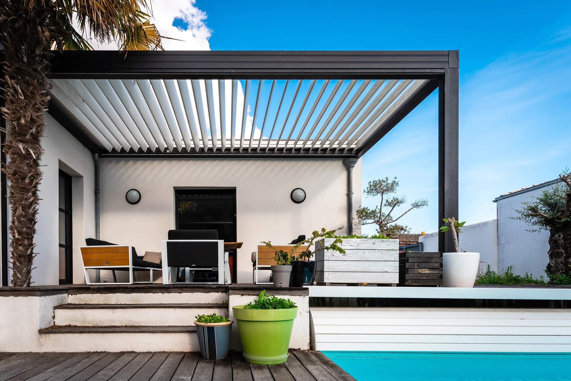 pergola moderne dans une maison contemporaine entourée d'un jardin et d'une piscine